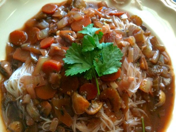 Vegan bourguignon over a plate of rice noodles
