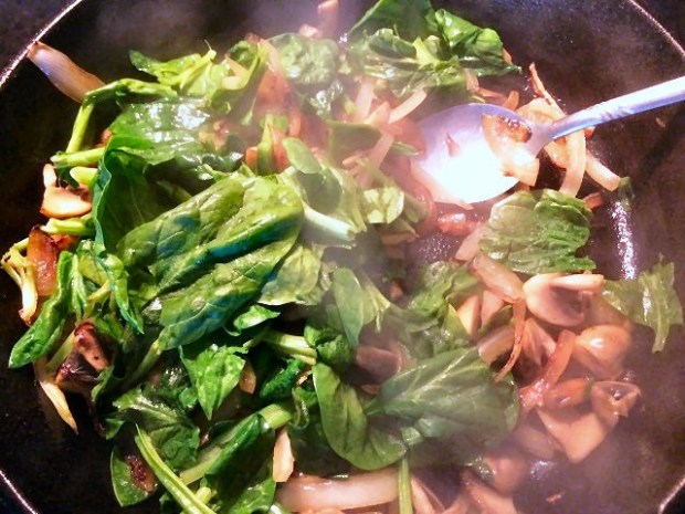 Adding in the spinach to cook